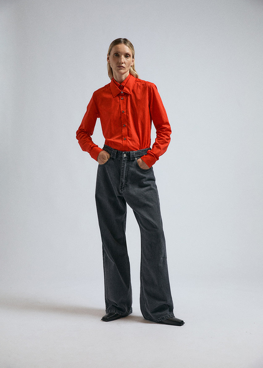 Woman wears JordanLuca's FW24 black wide leg Insignia jeans, paired with a red Joker shirt.